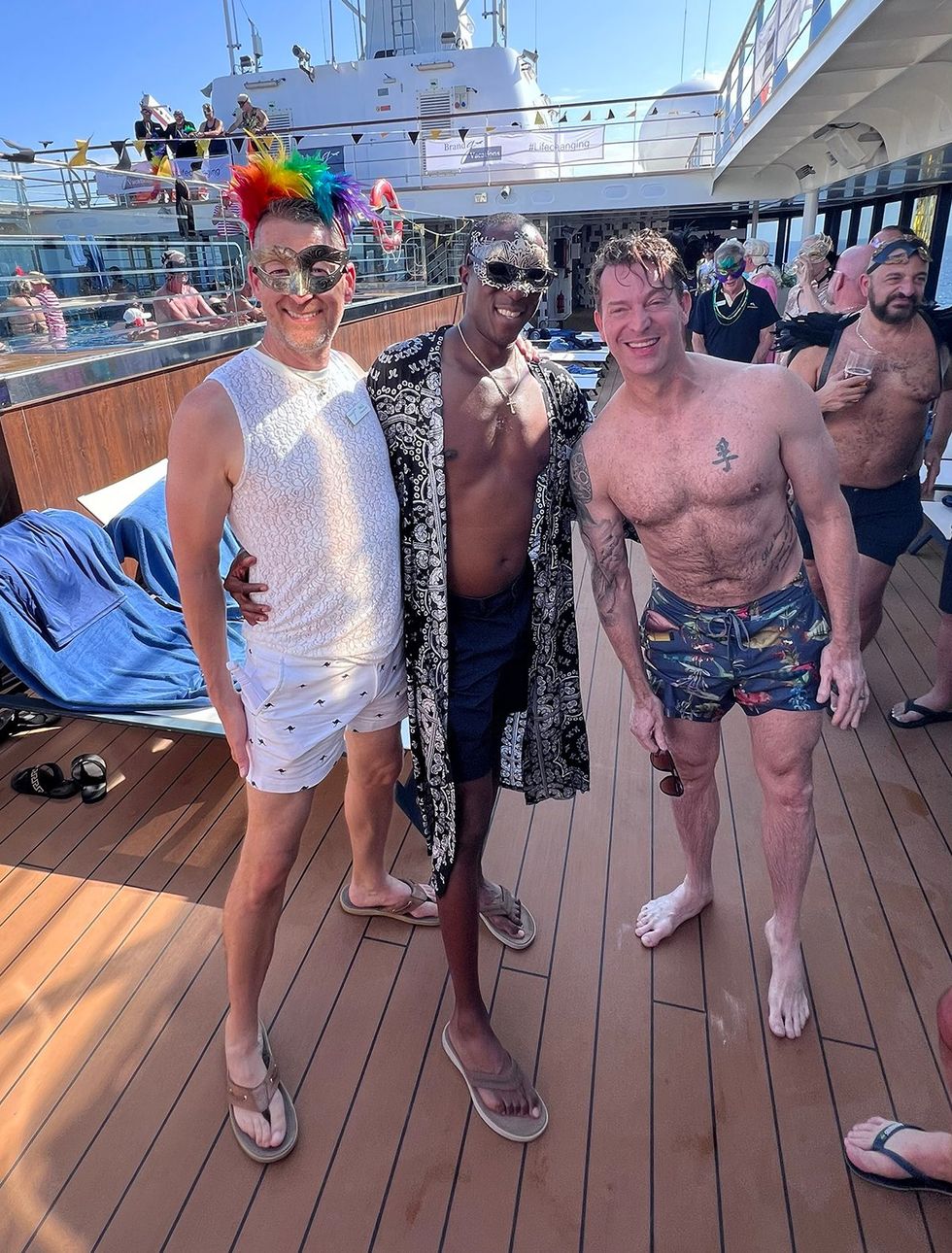 Finding community on our first luxury LGBTQ+ cruise. The author (left) and husband (center) make a new friend with help from Brand g Vacations