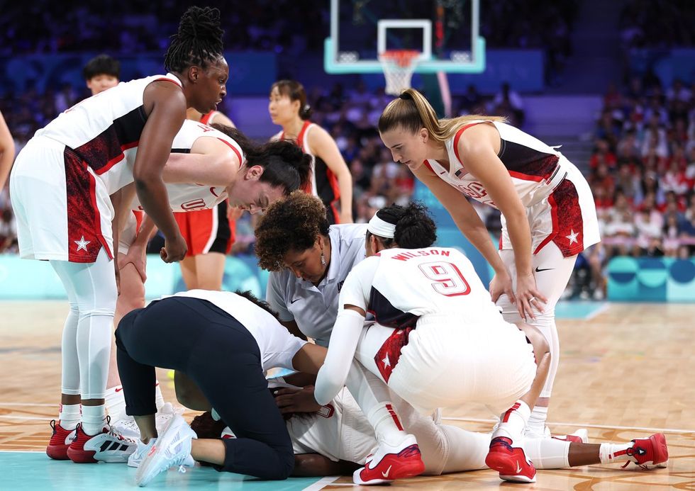 LILLE, FRANCE - JULY 29: Chelsea Gray #8, Breanna Stewart #10, Sabrina Ionescu #6, and A'Ja Wilson #9 of Team United States join medical staff in checking on Kahleah Copper #7 of Team United States during the Women's Group Phase - Group C game between Japan and United States on day three of the Olympic Games Paris 2024 at Stade Pierre Mauroy on July 29, 2024 in Lille, France. (Photo by Gregory Shamus/Getty Images)